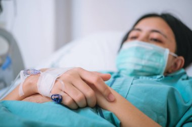 Genç kadın hasta yakından intravenöz normal salin ile hastane yatağında yatıyordu