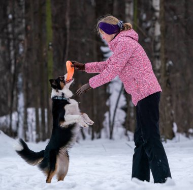Frizbi kenar kömür ocağı köpek ile karda oynayan kız