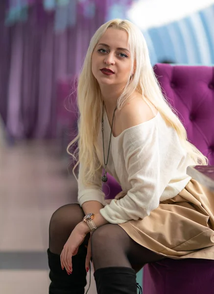 Beautiful young girl in a cafe in blue and burgundy tones