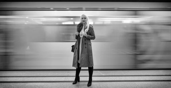 Beautiful young girl in the subway on a blurred background in train traffic