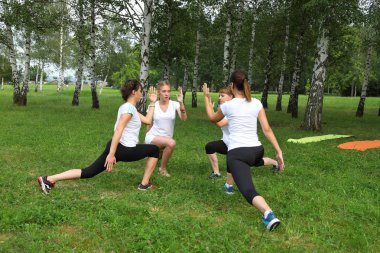 Güzel genç kadın Park yeşil çimenlerin üzerinde egzersiz germe yapıyor