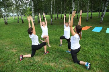 Güzel genç kadın Park yeşil çimenlerin üzerinde egzersiz germe yapıyor