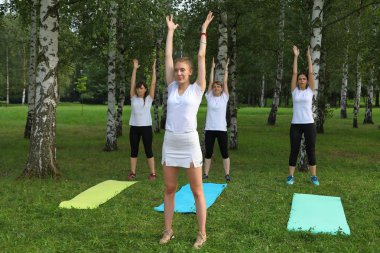 Güzel genç kadın Park yeşil çimenlerin üzerinde egzersiz germe yapıyor