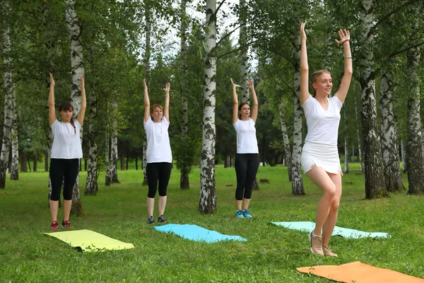 Güzel genç kadın Park yeşil çimenlerin üzerinde egzersiz germe yapıyor