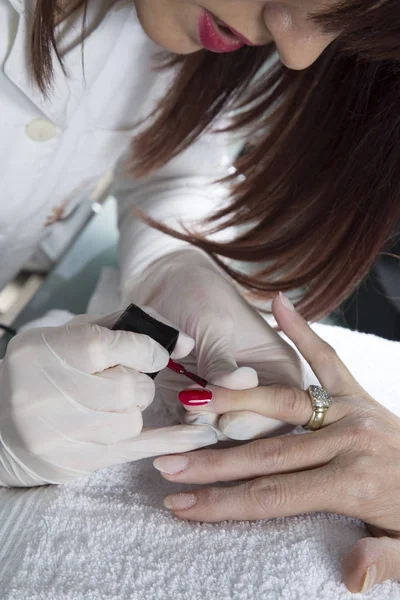 Manicurist With Protective Gloves Painting Fingernails With Red Nail Polish On White Soft Towel Closeup
