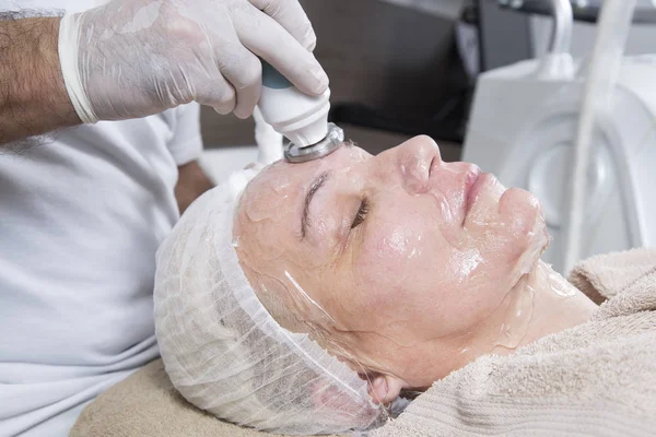 Lazer ve ultrason Anti Aging yüz almak yüz tedavi orta yaşlı kadın Masaj gözleri kapalı ve güzellik salonu Closeup dinlenme ile yalan süre