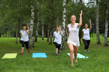 Güzel genç kadın Park yeşil çimenlerin üzerinde egzersiz germe yapıyor