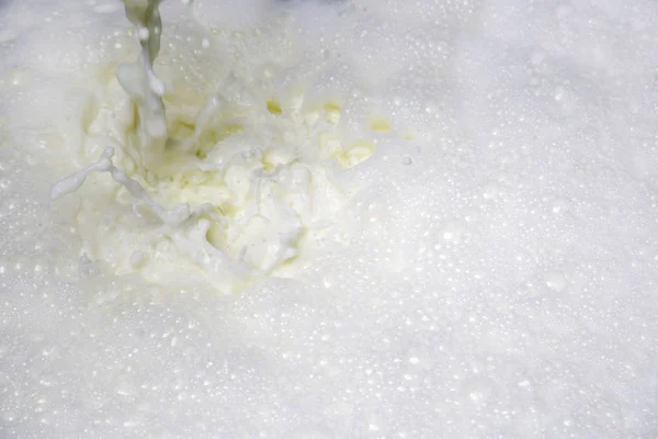 牛奶从水龙头流出 使白色泡沫和气泡特写 图库图片