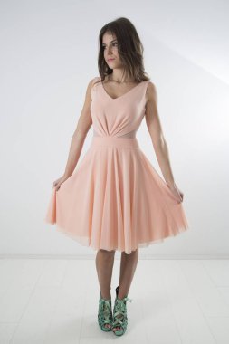 Pembe yaz elbise ve turkuaz yüksek topuklu, beyaz arka planda zarif gülümseyen kadın tam uzunluklu stüdyo çekim