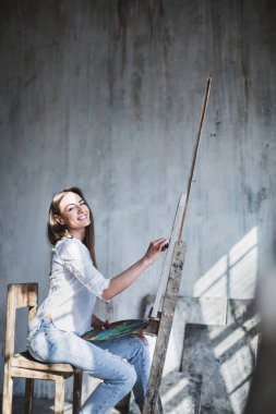 Güzel esmer kadın modern sanatçı resim oilpaints Studio gülümseyerek. Yaratıcılık kavramı.
