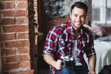 Erkek fotoğrafçı. Genç gülümseyen adam bir kamera evde tutuyor. 