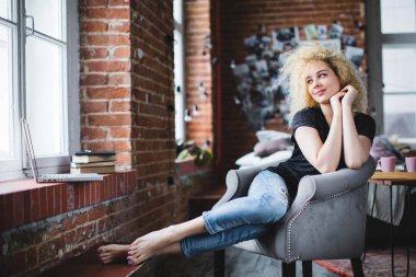 Hayalperest. Modern bir evde bir sandalyede genç güzel kadın / çatı. 