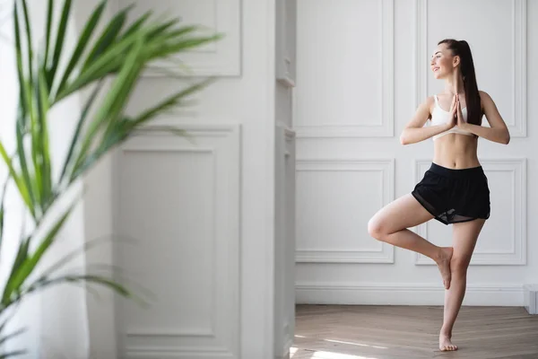 Glad Ung Kvinna Träna Inomhus Gör Yogaövning Stående Vrksasana Hållning — Stockfoto