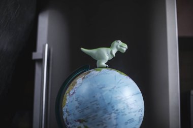 Küresel ısınma. Dinozorlar oyuncak dünya modeli koyu arka plan üzerinde.