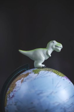 Tyrannosaurus dinozorlar oyuncak dünya modeli koyu arka plan üzerinde. Küresel ısınma ve felaket kavramı.