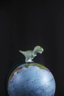Tyrannosaurus dinozorlar oyuncak dünya modeli koyu arka plan üzerinde. Küresel ısınma ve felaket kavramı.