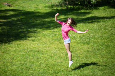 Mutlu kadınla çimenlerin üzerinde atlama. Egzersiz açık.