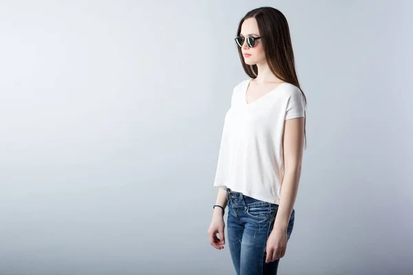 一个戴着太阳镜的现代女人的时尚肖像 白色衬衫和牛仔裤 — 图库照片