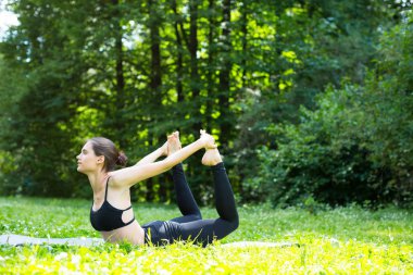 Genç kadın parkta yeşil çimenlerin üzerinde yapıyor.