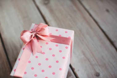 Ahşap eski masa üzerinde pembe kurdele ile hediye.