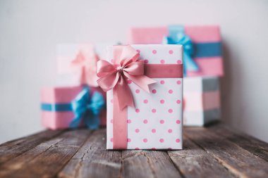 Ahşap arka plan üzerinde pembe fiyonklu şık el yapımı hediye kutusu.