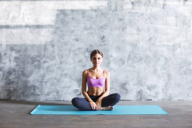 Mat intdoors üzerinde oturan bir genç ve güzel fitness kız portresi. 
