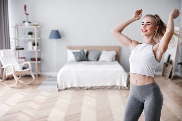 Young sporty woman doing morning exercise standing in living room. — Stock Photo, Image