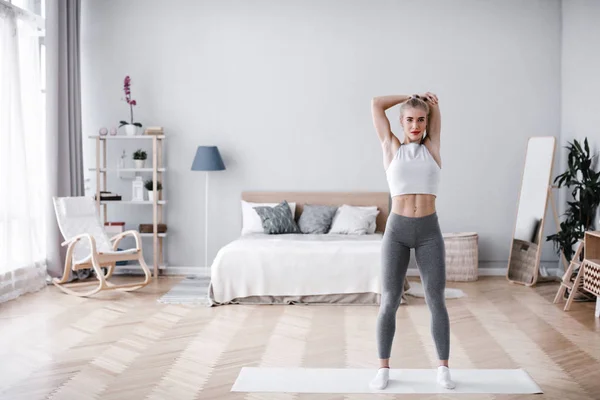 Träning på hemmaplan. Vacker atletisk kvinna göra övningar på rummet. — Stockfoto