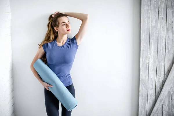 Gezonde fitness vrouw met blauwe yoga mat thuis voor training. — Stockfoto