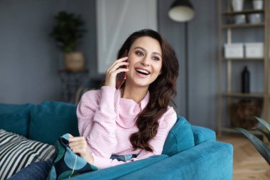Genç neşeli kadın rahat koltukta oturan cep telefonunda söz