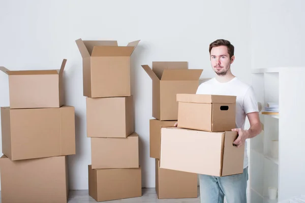 Jovem com caixas de papelão em novo apartamento . — Fotografia de Stock