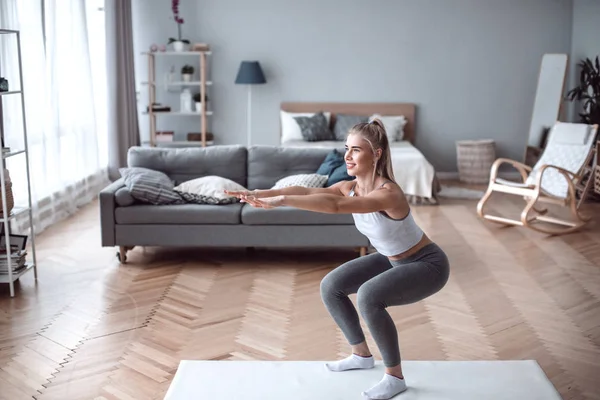 Mujer joven haciendo ejercicio en casa en una sala de estar. — Foto de Stock