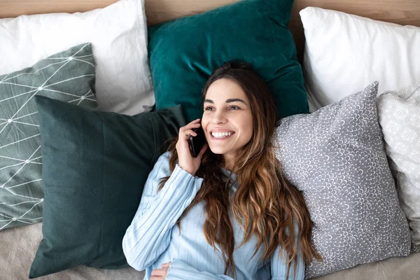 Mujer feliz hablando por teléfono en la cama en casa . —  Fotos de Stock