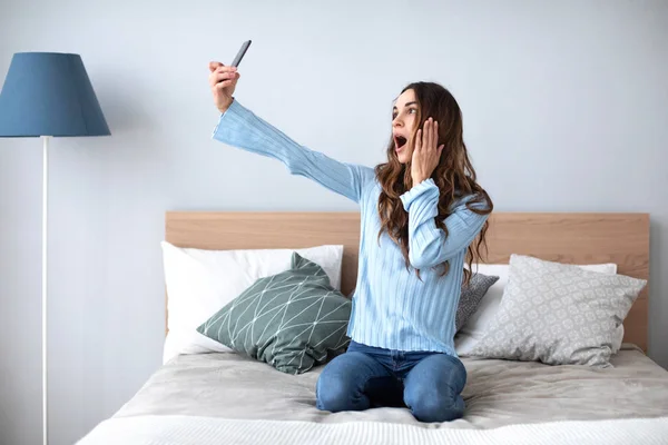 Fotografía de una mujer tomando selfie con su teléfono celular mientras estaba sentada en la sala de estar . —  Fotos de Stock