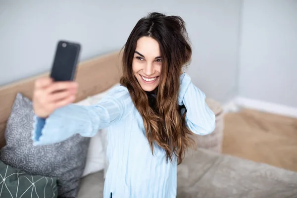 Beautiful woman at home on the couch do selfie on cell phone. — Stock Photo, Image