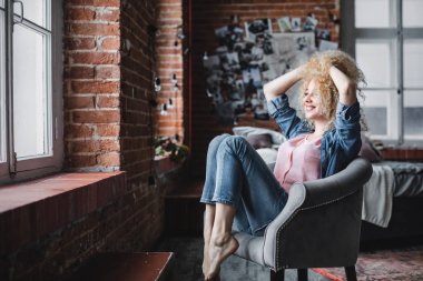 Güzel sarışın kadın kıvırcık saçlı relax modern loft veya ev.