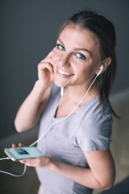 Kulaklık mutlu genç gülümseyen kadın akıllı telefon ile müzik dinlemek.