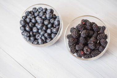 Ahşap bir masa üzerinde yaban mersini ve blackberry closeup ile plakalar. 