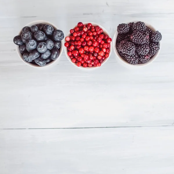 Berries platter with fresh organic red cowberry, blueberry and blackberry wooden table, top view. — Stock Photo, Image