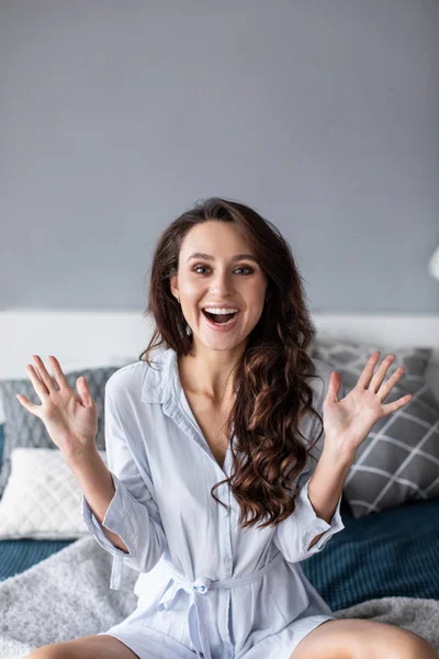 Feliz linda senhora sentada na cama dentro de casa . — Fotografia de Stock