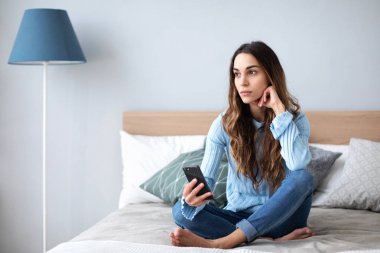 Kanepede evde akıllı telefon ile Üzgün kadın.