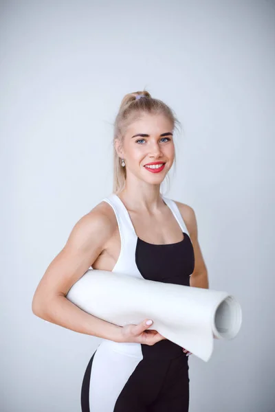 Portret van een mooie atletische vrouw met mat. — Stockfoto