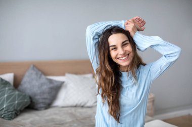 Kanepede gülümseyen kadın ve kameraya bakar.