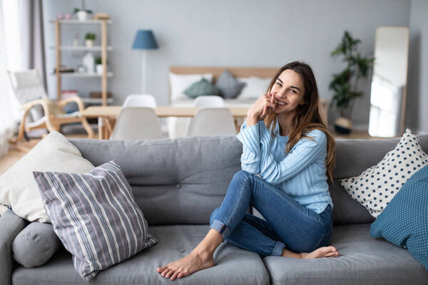 Relaxed smiling woman sitting on sofa at home. Domestic life.