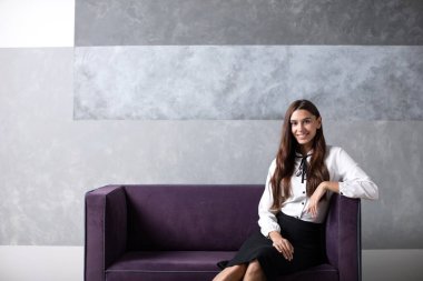 Kanepede oturan kadın ofis çalışanı. Uzak çalışma.