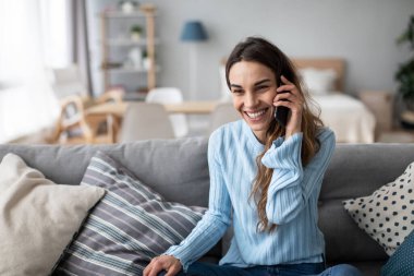 Kanepede otururken cep telefonuyla konuşan bir kadın. İçeride pozitif bir kızın portresi..