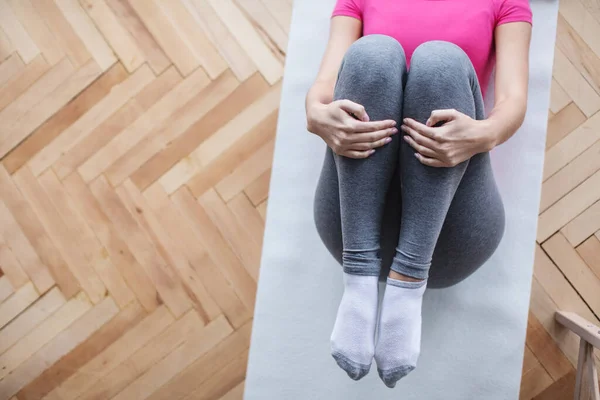 Woman doing indoor exercises on a sports mat top view. Home yoga.