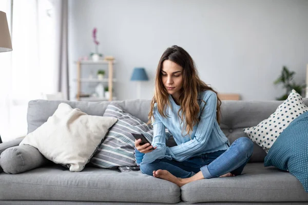 Mujer Sonriente Relajarse Sentarse Sofá Casa Sostener Teléfono Celular Compras —  Fotos de Stock