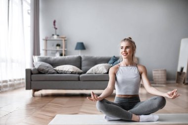 Evde egzersiz yapan zinde bir genç kadın. Yoga zamanı..