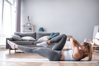 Sıska sporcu kız evde karın kası egzersizi yapıyor. Sağlıklı kadın içeride egzersiz yapıyor..